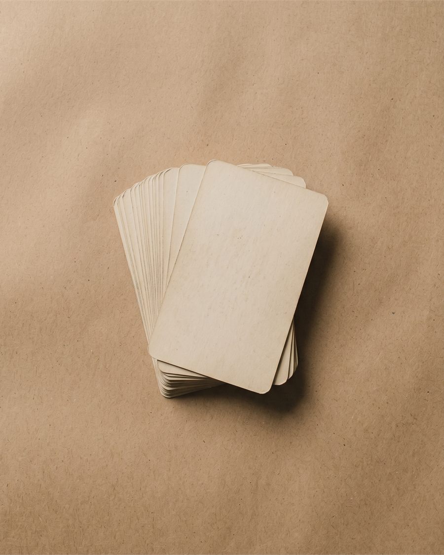 A worn tarot deck lying face down on kraft paper.